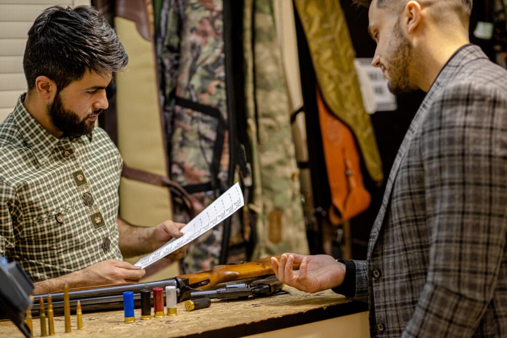 Confident salesman checking document in guns store