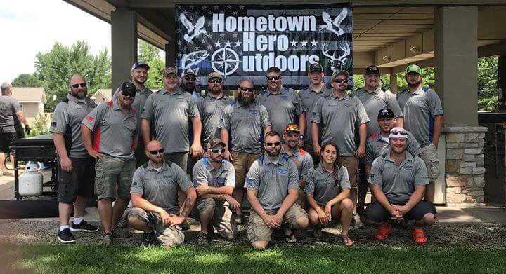 Group photo of the original Hometown Hero Outdoors founding members and volunteers, standing together in front of an HHO banner during an early event.